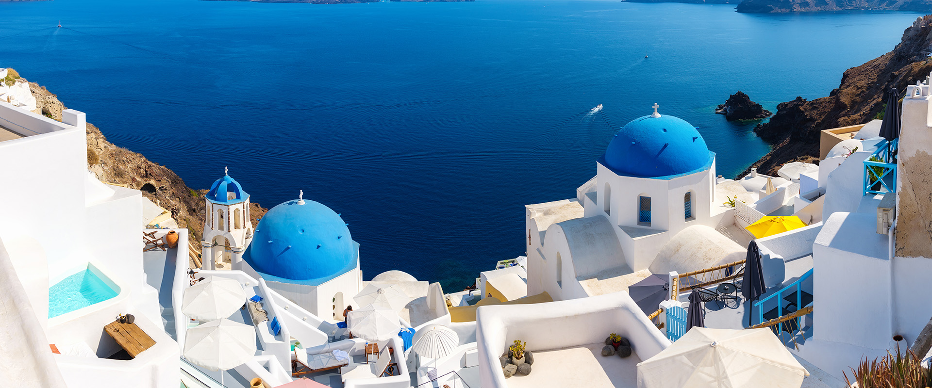 Santorini, Greece. Panoramic view of traditional houses in Santorini. Small narrow streets and rooftops of houses, churches and hotels. Oia village, Santorini Island, Greece. Travel and vacation photography.