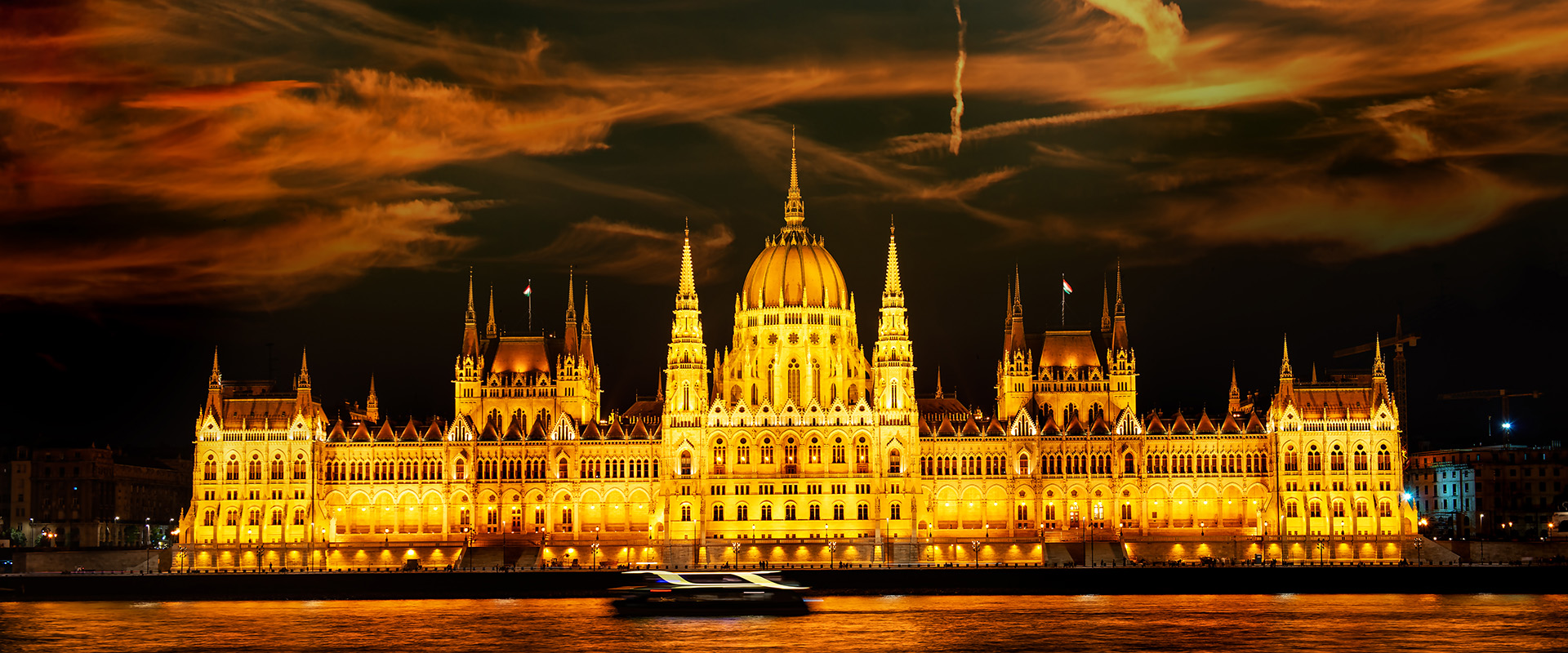 Facade of illuminated Budapest Parliament under cloudy sky, Hungary