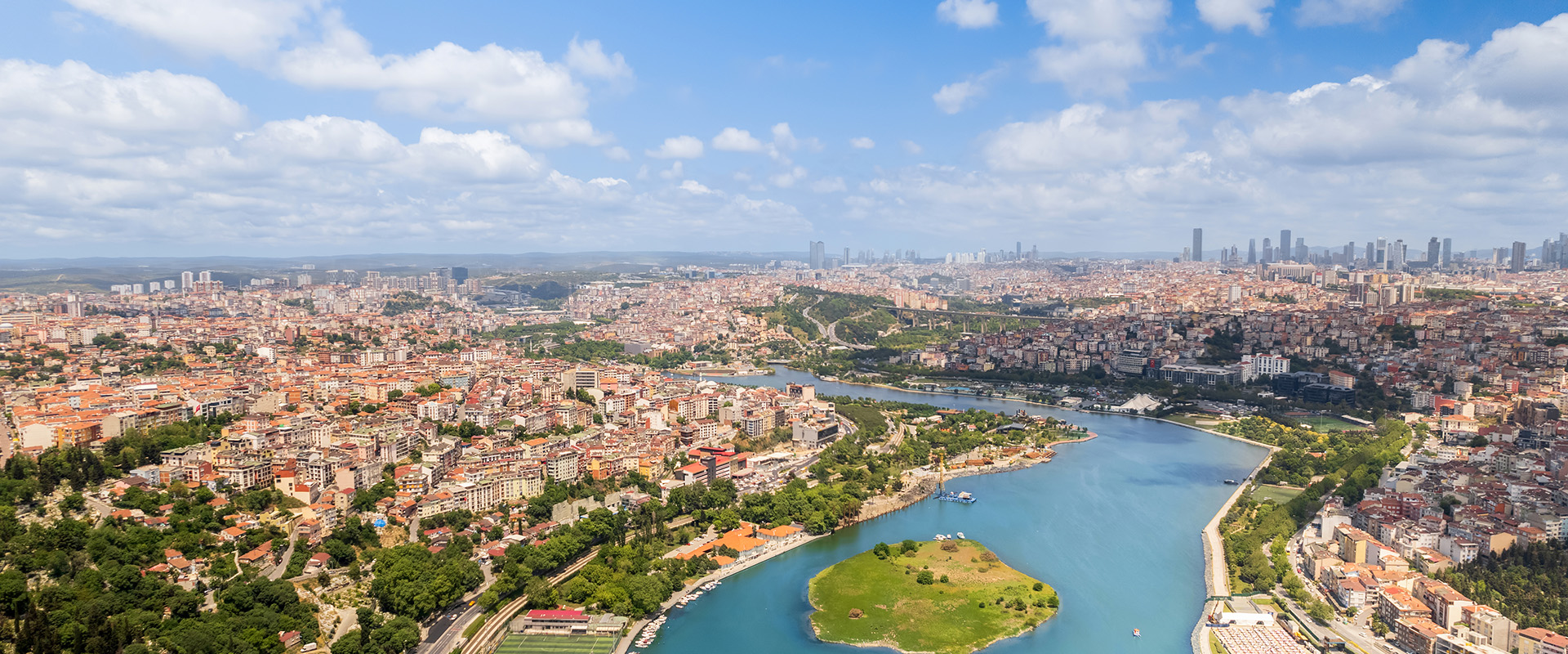 Aerial drone panoramic view of Istanbul, Turkey. Balat district with multiple residential buildings and greenery, Golden Horn waterway, downtown on the background