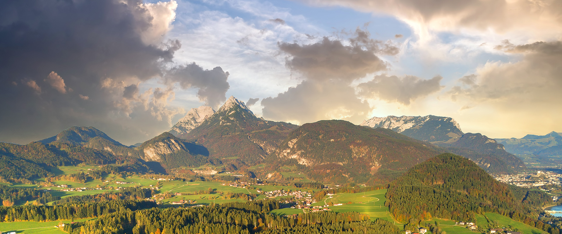 Aerial view of green meadows with villages and forest in austrian Alps mountains.